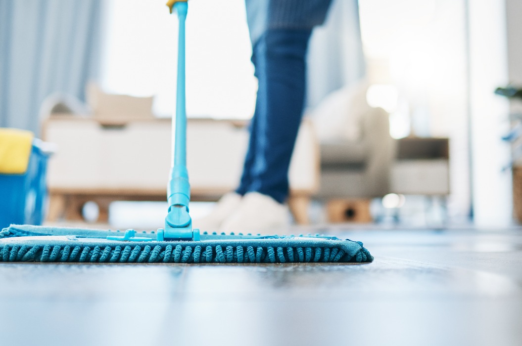 Hauswirtschaft, Reinigung und Hausmädchen mit einem Mopp, um den Boden im Wohnzimmer eines Hauses zu reinigen. Weibliche Hausangestellte, Putzfrau und Hausfrau, die den Boden in ihrem Haus von Bakterien, Staub und Schmutz befreit.